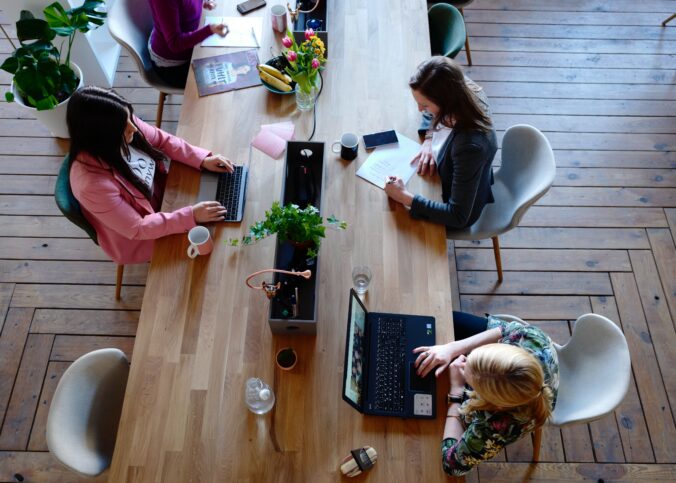 Bilden visar människor i ett coworking space eller ett kontorslandskap. Ljudabsrobenter som takabsorbenter och väggabsorbenter är viktiga för att skapa en tystare och behagligare arbetsmiljö.